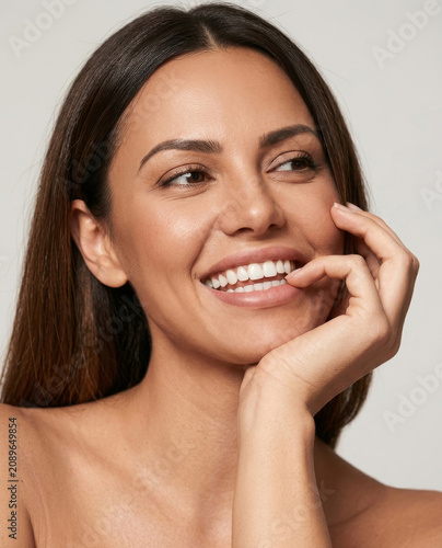Close-up portrait of a beautiful young woman with long brown hair smiling broadly and looking to the side