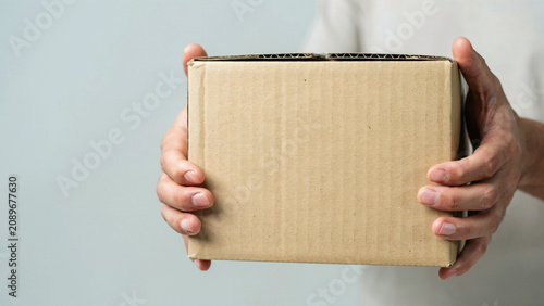 Person holding a small brown cardboard box for delivery