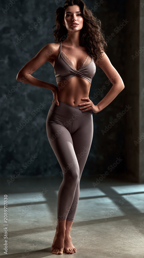 Fototapeta premium fitness woman in sensual sportswear posing confidently in studio, athletic female model showcasing modern activewear in studio portrait, confident sporty woman wearing fashionable fitness apparel 