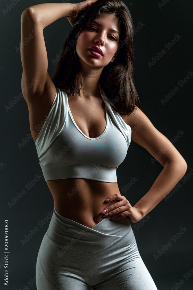 Fototapeta premium fitness woman in sensual sportswear posing confidently in studio, athletic female model showcasing modern activewear in studio portrait, confident sporty woman wearing fashionable fitness apparel 