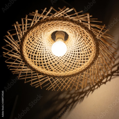 Woven rattan pendant lamp with illuminated bulb, boho interior