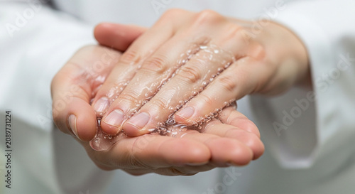 Hands applying clear gel scrub with fine particles for cleansing and exfoliation.