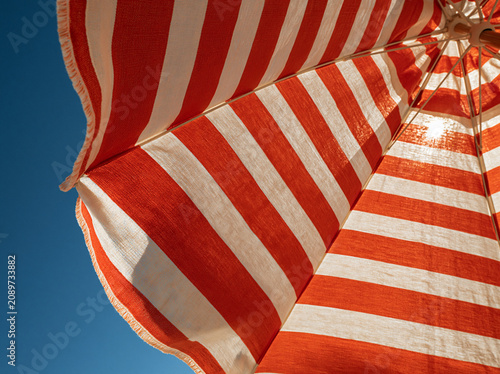 Striped beach umbrella fabric against blue sky