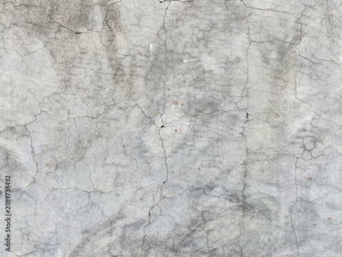 A detailed close-up of a weathered concrete wall surface, showing prominent cracks and imperfections.