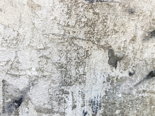 A close up view of a weathered concrete wall surface featuring peeling plaster and aged rustic textures.