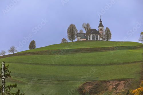 Fotografie Sorrowful Mother of God church (Cerkev Zalostne Matere Bozje) on a hilltop of the Prealps in a misty, autumnal late afternoon