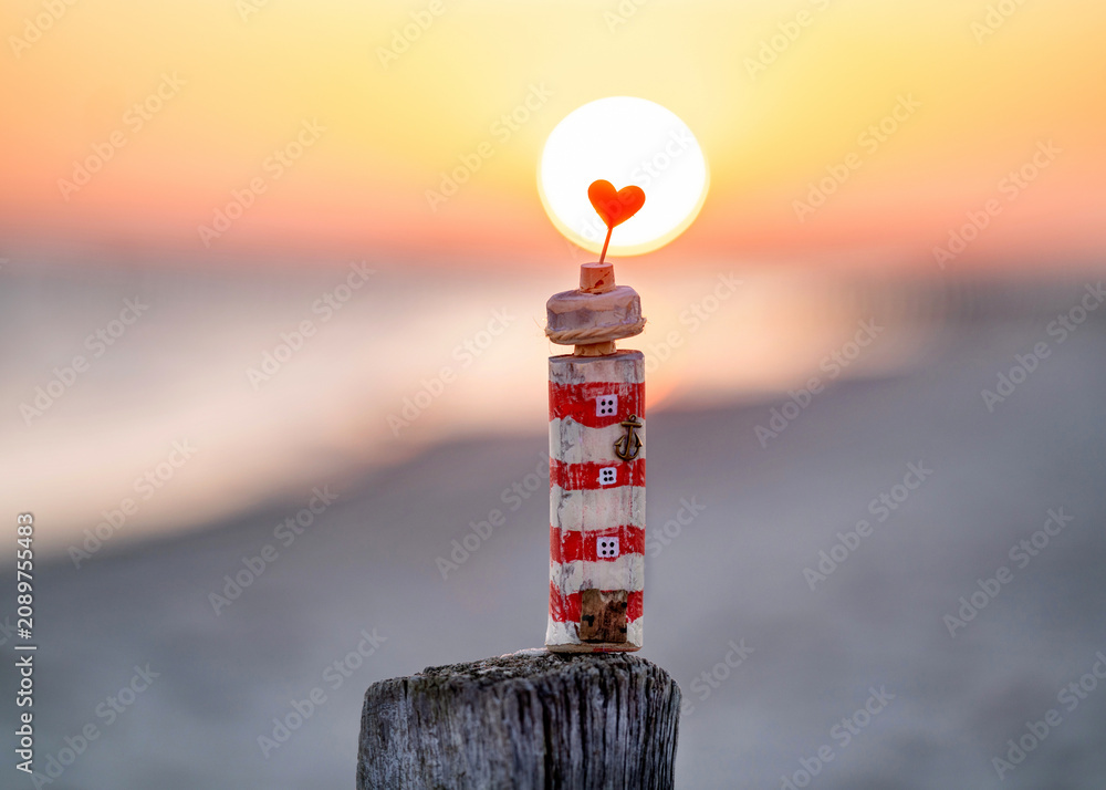 Naklejka premium self-made lighthouse from driftwood at the beach in sunrise