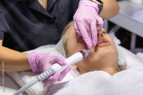 Obraz na płótnie Close-up of a cosmetologist performing a hydradermabrasion facial around the mouth area using a professional skincare device for deep cleansing and skin rejuvenation