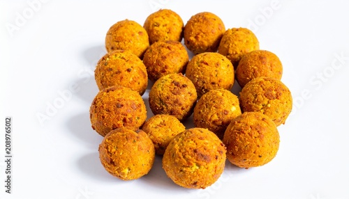 Golden fried falafel balls on white background, one broken open showing crumbly yellow-green interior, crisp texture and appetizing lighting emphasizing savory snack appeal.