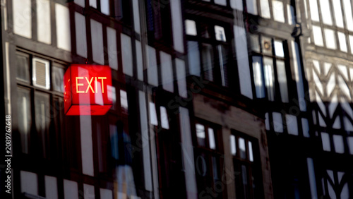 Photos Glowing red exit sign with architectural reflection, escape and emergency concep