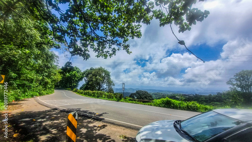 Scenic winding mountain road along the Kumily-Kattappana-Adimali-Munnar route through the lush Western Ghats of Kerala, India, under dramatic monsoon clouds and vibrant greenery.