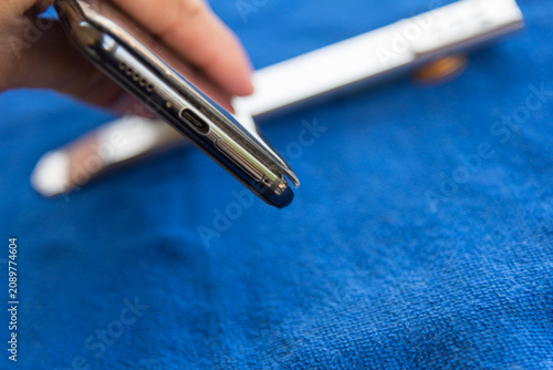 Swollen smartphone battery lifting up the back cover plate, broken electronic device isolated on table 