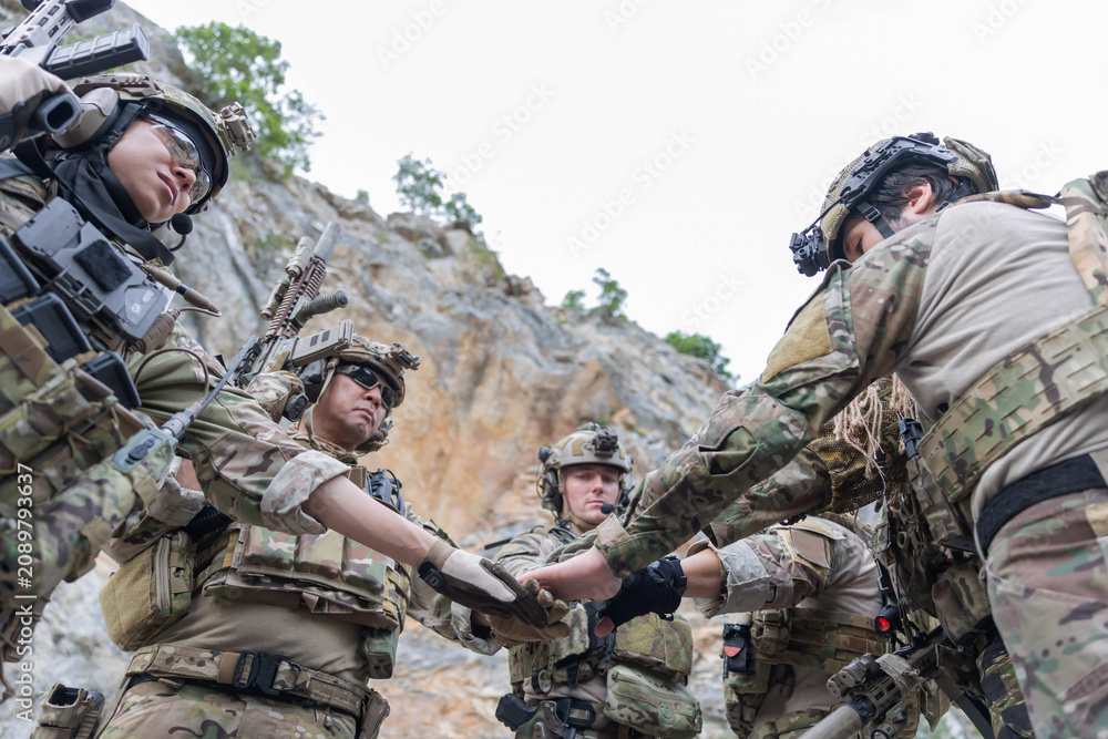 Fototapeta premium Soldiers joint hand for teamwork