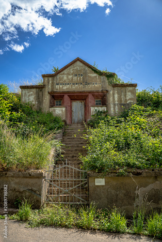 ehemalige Wasserwerk aus dem Jahr 1929, das sich still zwischen Weinreben und wildem Grün versteckt. Die Fassade trägt die Spuren der Zeit mit einer Würde, die man heute nur noch selten findet. Währen