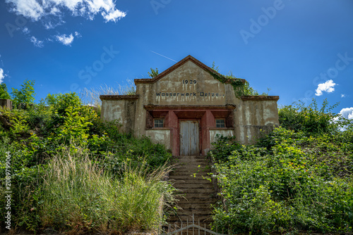 ehemalige Wasserwerk aus dem Jahr 1929, das sich still zwischen Weinreben und wildem Grün versteckt. Die Fassade trägt die Spuren der Zeit mit einer Würde, die man heute nur noch selten findet. Währen