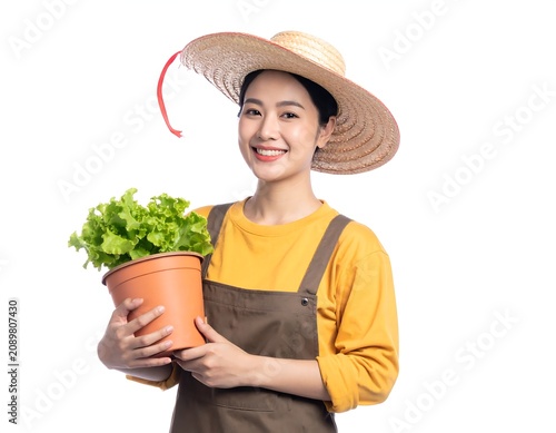 A smiling woman in a yellow shirt and brown apron holds a potted plant