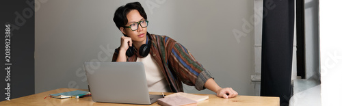 Fotografi Stylish Asian man immersed in creativity during a productive work session at a c