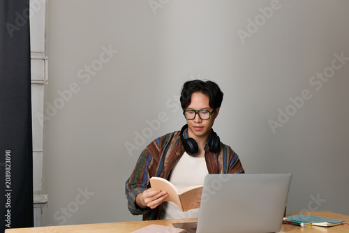 Photography Stylish young man immersed in reading at a modern workspace in a chic urban sett