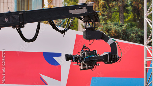 фотографія Large television camera on a jib crane at an outdoor broadcast event with a colo