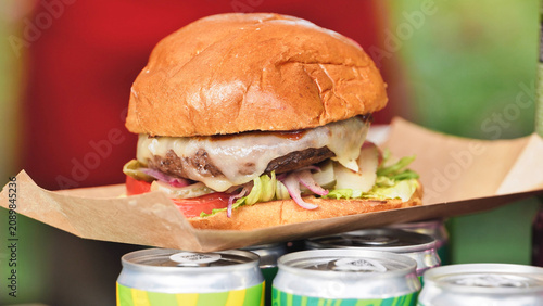 Juicy cheeseburger with melted cheese sitting on beverage cans