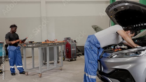 Worker team working service maintenance EV car balance battery and DC Inverter engine system checking in EV Auto service workshop
