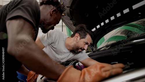 Worker in EV garage help friend service maintenance High Volt Power line in Electric Car in EV workshop auto service.