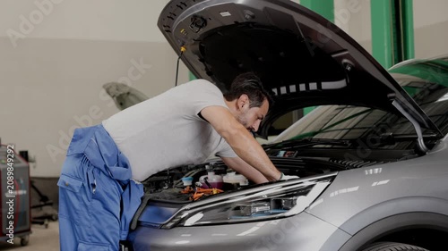Engineer technician male worker EV car auto service checkup service maintenance electricity vehicle check cable DC Inverter and Controller.