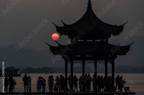 Photography Sunset silhouette of pavilion and visitors at West Lake, Hangzhou, China