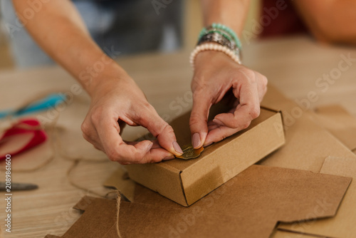 Female hands packaging a small box with string and label