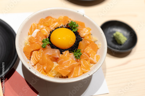 Japanese fresh raw salmon rice bowls topped with raw egg yolks and black caviar, served alongside miso soup and wasabi paste.