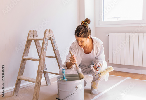 Foto Woman mixing paint in bucket during home renovation