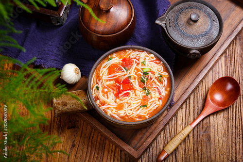 Bild auf Leinwand Tomato Noodle Soup with Enoki Mushrooms on Rustic Wooden Table