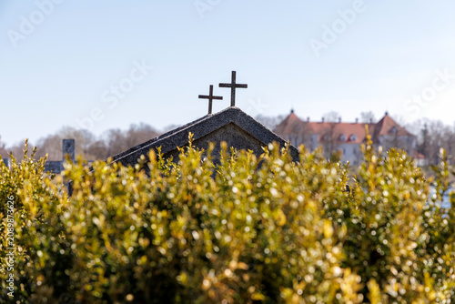 Fotografía Grave Crosses on Roof Over Blurred Green Leaves