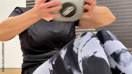 A woman performing exercises with a medicine ball for core strength in a gym. She uses different movements to engage her muscles