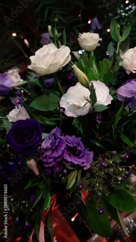 Fresh flowers arranged in a glass vase as an elegant centerpiece in an indoor event setting. Decorative floral arrangement enhancing the atmosphere of a social celebration or reception.