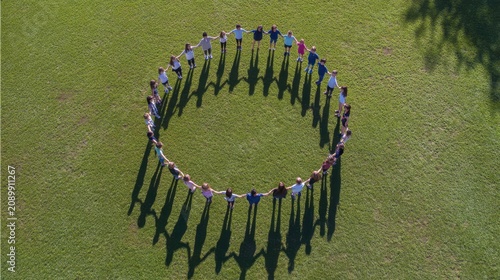 People holding hands in a circle on green field