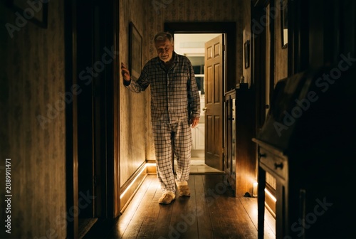Senior man walking to bathroom at night guided by warm motion sensor lights along hallway, night safety at home