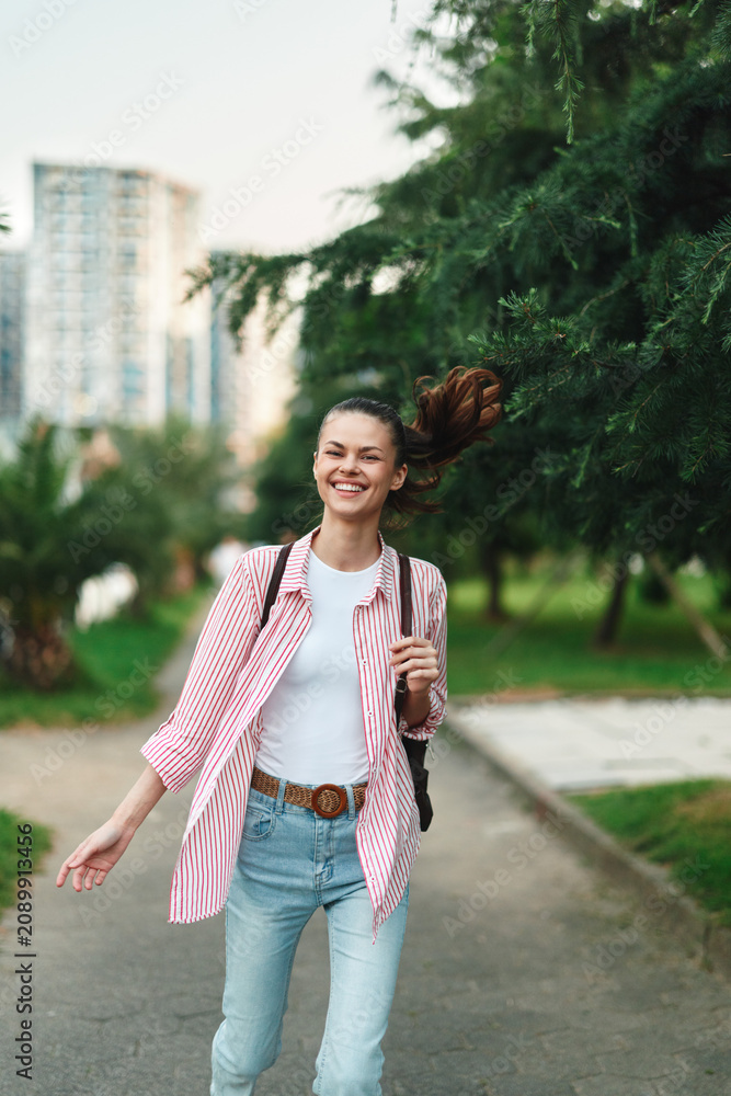 Naklejka premium Woman outdoors, smiling and relaxed, in casual fashion at a park with greenery, daylight and breeze, capturing a bright lifestyle moment.
