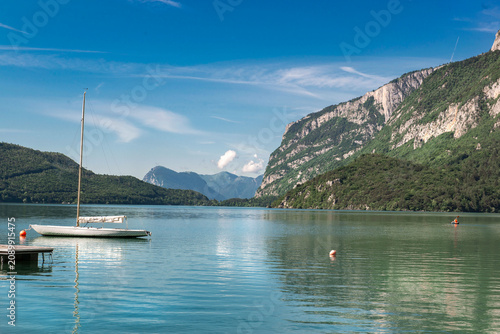pleasure boat moored to a pontoon on a lake in the Dolomites with mountain ba...