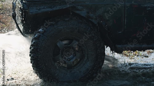A powerful, dirty SUV is washed with a hose. Close-up of the dirty tire. Concept of motorsports, adventure, and extreme sports