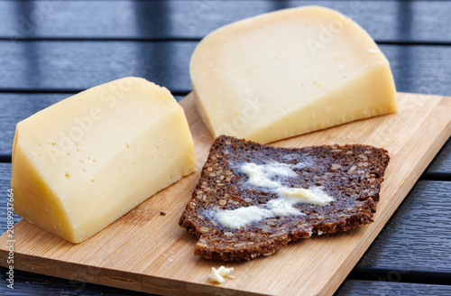 Sourdough wholegrain rye bread  with melting butter, served with cheese on a wooden board.