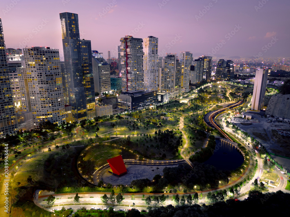 Fototapeta premium Dusk Aerial Cityscape with Purple Sky Over Urban Park and Glowing Skyscrapers in Mexico