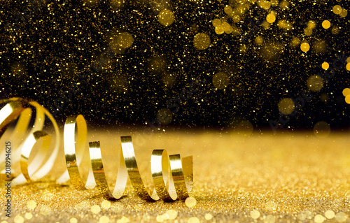 Obraz na plátně Christmas holidays background - golden ribbon, glitters and bokeh effect on blac