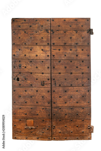 Front view of a weathered antique wooden door with two leaves, reinforced with decorative iron studs and historic blacksmith hardware, dating from the medieval or renaissance period, isolated