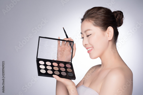 Canvastavla Smiling young woman holding eyeshadow palette and makeup brush
