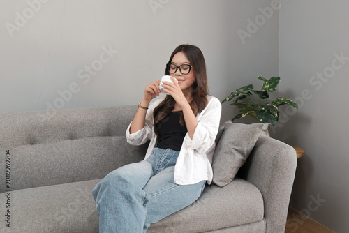 Young Asian Indonesian Woman Enjoying Aroma of Fresh Coffee While Relaxing at Home