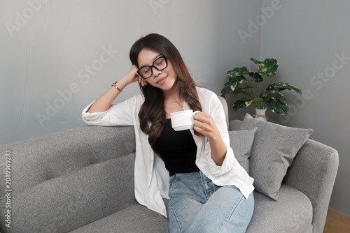 Young Asian Indonesian Woman Enjoying Quiet Coffee Break with Eyes Closed at Home