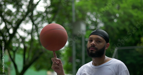 Canvas Print African American man spinning basketball close-up on finger, expression of focus