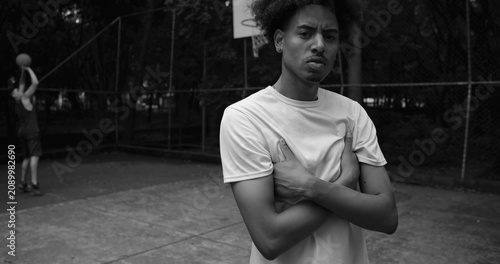 Billede på lærred African American man standing confidently on outdoor basketball court with arms