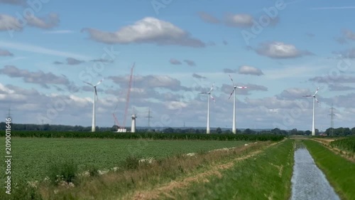 Modern wind turbines in agricultural landscape under blue sky